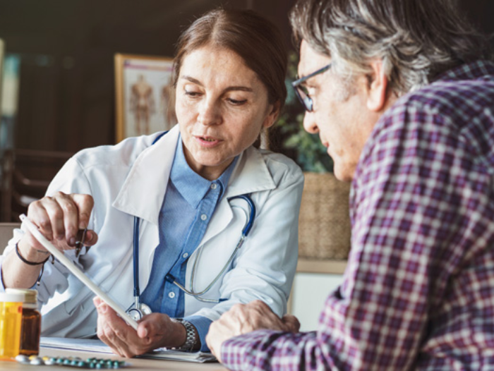 A doctor discusses member health plans with a patient and shows him a tablet